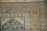 Distressed Malayer rug corner with worn texture and geometric borders in blue and sandalwood.