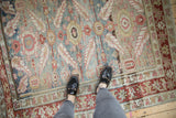 The soft, distressed texture and muted colors of an antique Karaja carpet seen underfoot.