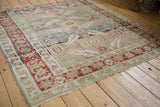 Angled view of a distressed antique Karaja rug highlighting the time-softened red and teal palette.