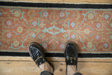 Soft texture of an antique Nichols rug's terracotta field with powder blue and jade Art Deco vines.