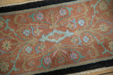 Close view of the even wool pile and scrolling floral vines on an antique Nichols rug.