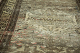 Distressed vintage Hamadan rug pile, showing beige field and intricate brown border.