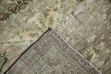 Corner of distressed Hamadan rug, highlighting worn beige pile and secured geometric border.