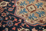 Hand-knotted Gorevan rug detail with navy field, meandering red vines, and sapphire blue border motifs.
