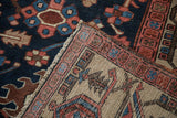 Vintage Gorevan rug corner, revealing hand-knotted foundation and geometric navy, blush border.