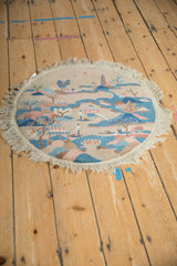 Angled view of a round Art Deco rug showing its Chinese garden landscape and full fringe.