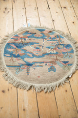 High-angle view of a vintage round Art Deco rug showing its full pictorial design and beige fringe.