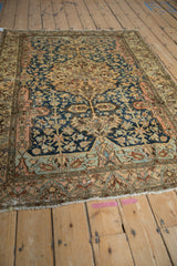 Angled perspective of an antique Malayer rug, showing the texture of its mostly even wear and detailed borders.