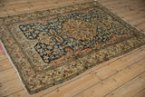 Angled view of an antique Malayer rug showcasing its navy blue field, central medallion, and sand borders.