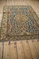 A view down the length of an antique Malayer rug, with its roundel medallion and navy vine field.