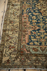 Meandering vine and floral details in the wide, sand-colored border of an antique Persian Malayer rug.