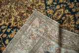 Corner of an antique Malayer rug folded back to reveal its hand-knotted foundation and weave.