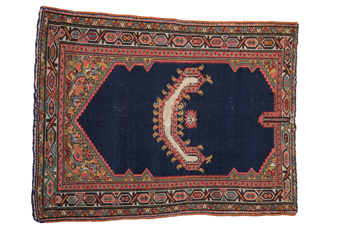 Antique Persian saddle cover rug with a navy field, central horn motif, and colorful geometric borders.