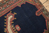 Angled view of an antique Persian rug's corner spandrel with geometric Herati-style motifs.