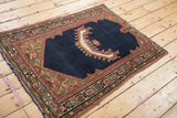 Side perspective of an antique saddle cover rug, highlighting the asymmetric horn motif and detailed spandrels.