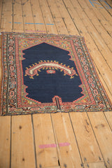Antique Persian saddle cover from a high angle, detailing its asymmetric shape and complex geometric borders.