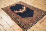 Angled view of an antique Northwest Persian saddle cover, highlighting its asymmetric horn motif and vibrant borders.