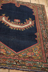 The horn-shaped motif and colorful spandrel on an antique Northwest Persian saddle cover's navy field.
