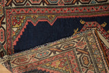 A folded corner of the antique Persian saddle cover reveals its navy pile and intricate woven foundation.
