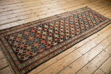 Lightly tattered side selvage and geometric charcoal, red, ivory pattern of Malayer rug.