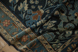 Folded corner of a fine Lilihan rug showing intricate floral motifs in charcoal navy, teal, and copper.