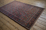 Full perspective of a vintage Sarouk rug's intricate cherry red and navy Herati design.