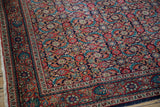 Corner detail of a vintage Sarouk rug showing the meandering vine border and navy blue Herati field.