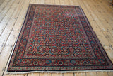 A traditional vintage Sarouk rug featuring a complex allover Herati pattern in cherry red and navy blue.