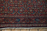 Detail of a vintage Sarouk's meandering vine and palmette border in red, navy, and teal.