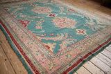 Oushak carpet detail: sprawling vines on a jade green field with cherry red and blush borders.