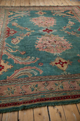 Patinaed jade green Oushak rug with blush palmette and scrolling vine motifs.