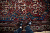 Serrated leaf and serpent motifs within the geometric pattern of an antique Qashqai carpet.