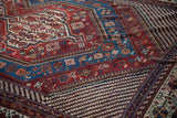 Detailed view of a Persian Qashqai carpet's layered borders with intricate geometric motifs in sapphire and burgundy.