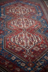 Perspective view along the linked medallions of an antique Qashqai rug in sapphire blue and burgundy.