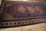 An antique Qashqai Persian carpet's intricate tribal design, viewed from an angle to show its full scale.