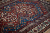 An angled view across the rich, geometric medallion and borders of an antique Qashqai carpet.