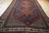 Low angle view of an antique Qashqai carpet, emphasizing the flow of its red and blue medallions.