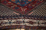 A stylized serpent motif alongside diagonal bud patterns on an antique Qashqai rug.