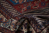 A folded section of an antique Qashqai carpet showing serrated leaf and serpent motifs.
