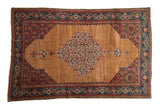 Antique Persian Senneh rug with a tiered Herati medallion on an abrash camel brown field.