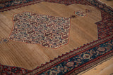 The distinct medallion and shaded camel brown field of a traditional antique Senneh rug.