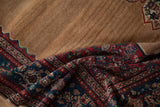 Draped antique Senneh rug with a shaded camel wool field and detailed sapphire blue border.
