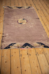 Angled view of an antique Peking rug runner, revealing its mauve open field and rippled side edges.