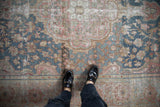 Abrashed distressed vintage Farahan Sarouk rug displaying muted blue and blush floral patterns.
