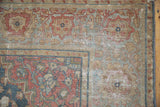 Distressed vintage Farahan Sarouk carpet corner showing faded floral borders and visible wear.