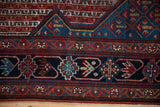 Antique Persian Qashqai runner's wide navy border, stylized plant motifs, and madder red.