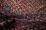 Folded antique Qashqai rug with navy border's vinery patterns and red, ivory diagonal field.