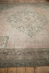 Vintage Oushak rug border with muted green motifs, charcoal, and dusty rose field.