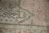 Vintage Oushak carpet detail: geometric border with scrolled tendrils in dusty rose, faded green, charcoal.