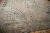 Faded geometric border design and visible pile wear on the vintage Oushak carpet.